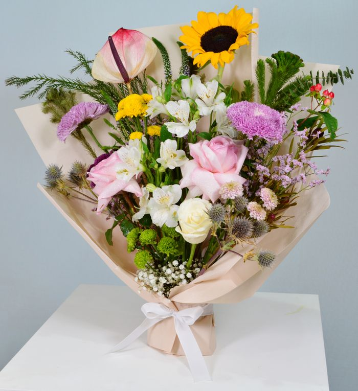 Offerings A colorful bouquet featuring a sunflower, roses, and mixed flowers arranged in Dubai.
