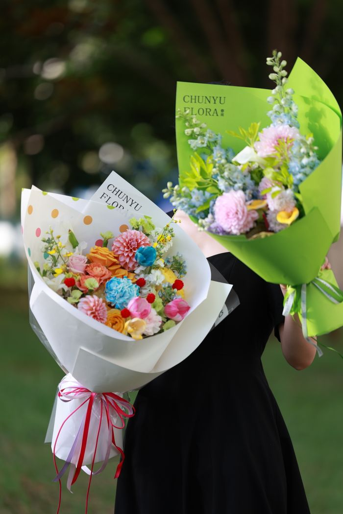 Colorful floral bouquets held by a person outdoors, capturing nature's beauty.