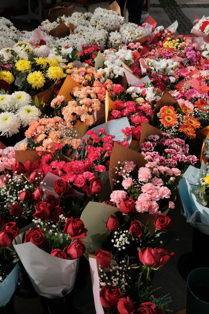 Offerings A vibrant assortment of colorful floral bouquets at an outdoor market, showcasing roses, daisies, and more.
